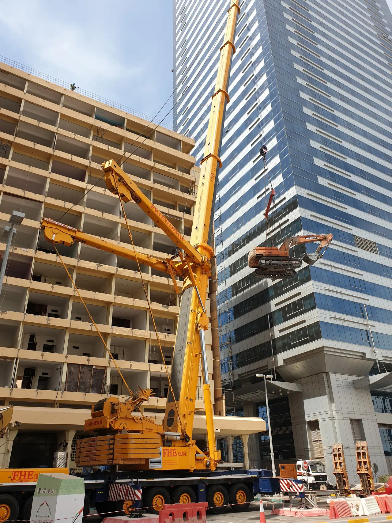 FHS crane lifting an excavator up the face of a building