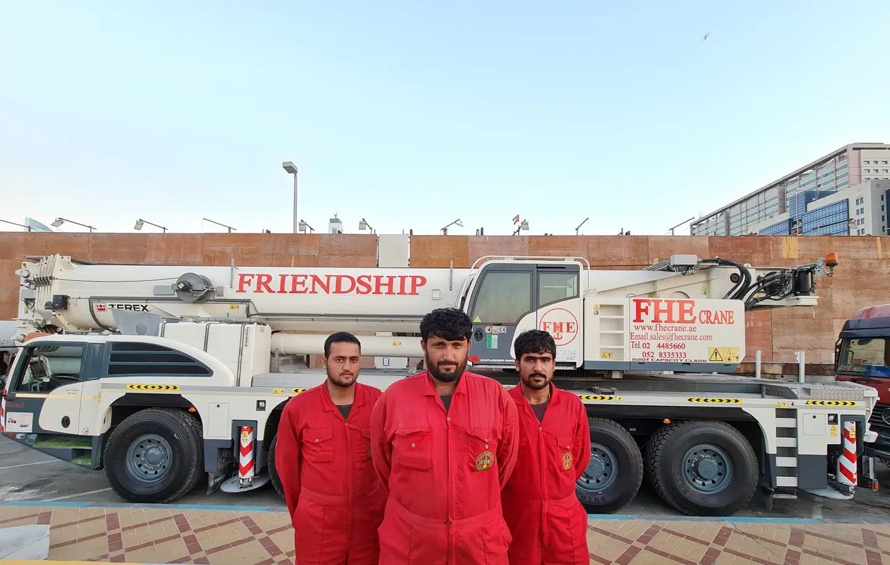 Three FHS crew in red coveralls in front of a Terex FRIENDSHIP crane