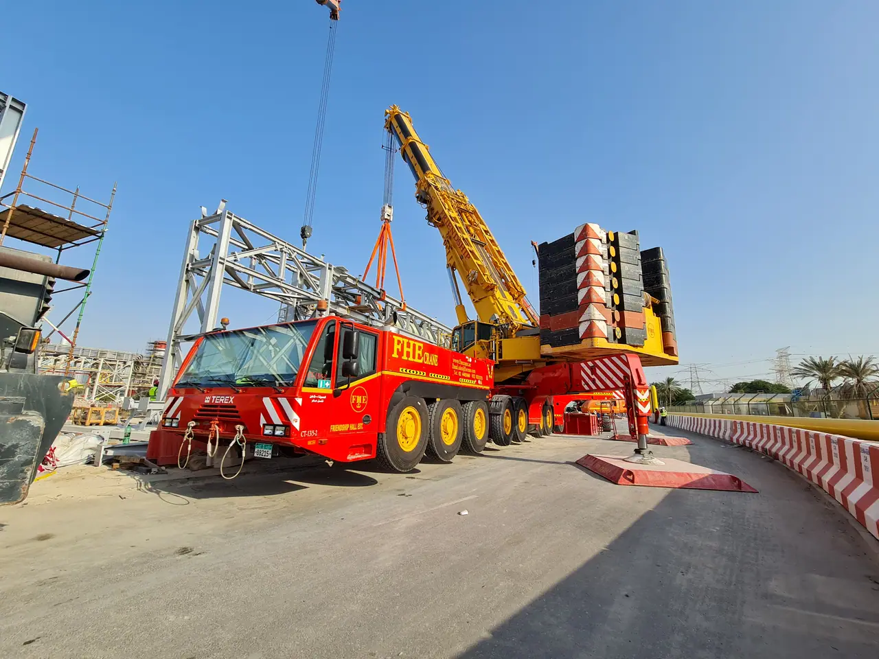 Red FHS heavy crane with superlift counterweight lifting a steel truss